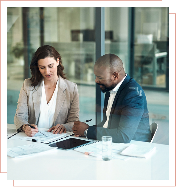 Two colleagues discussing documents at table.