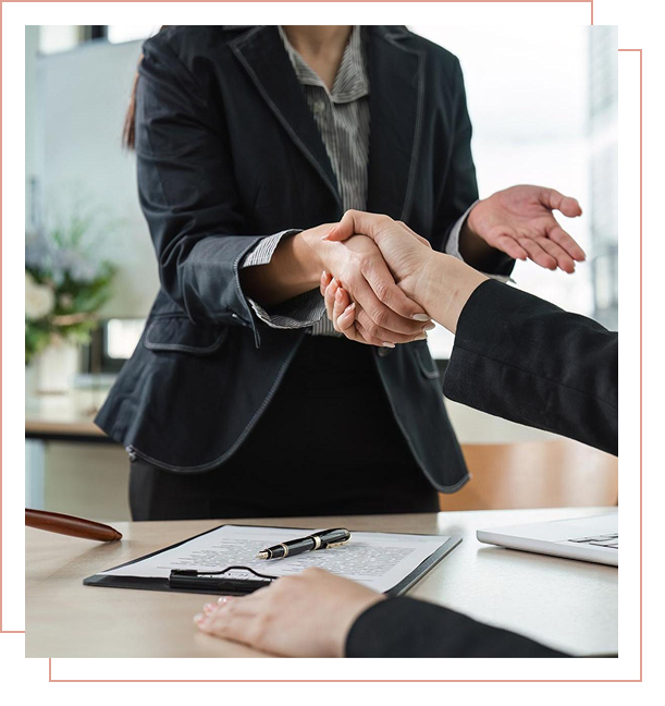 Business handshake over a desk with documents.