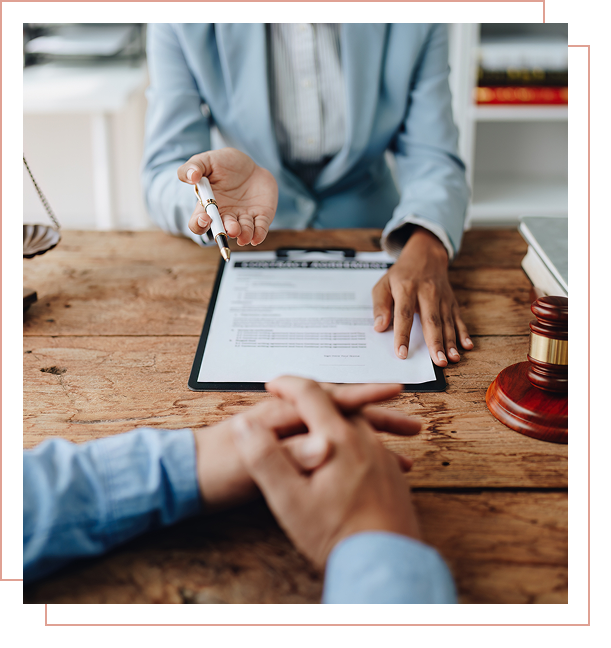 Lawyer discussing document with client at desk.