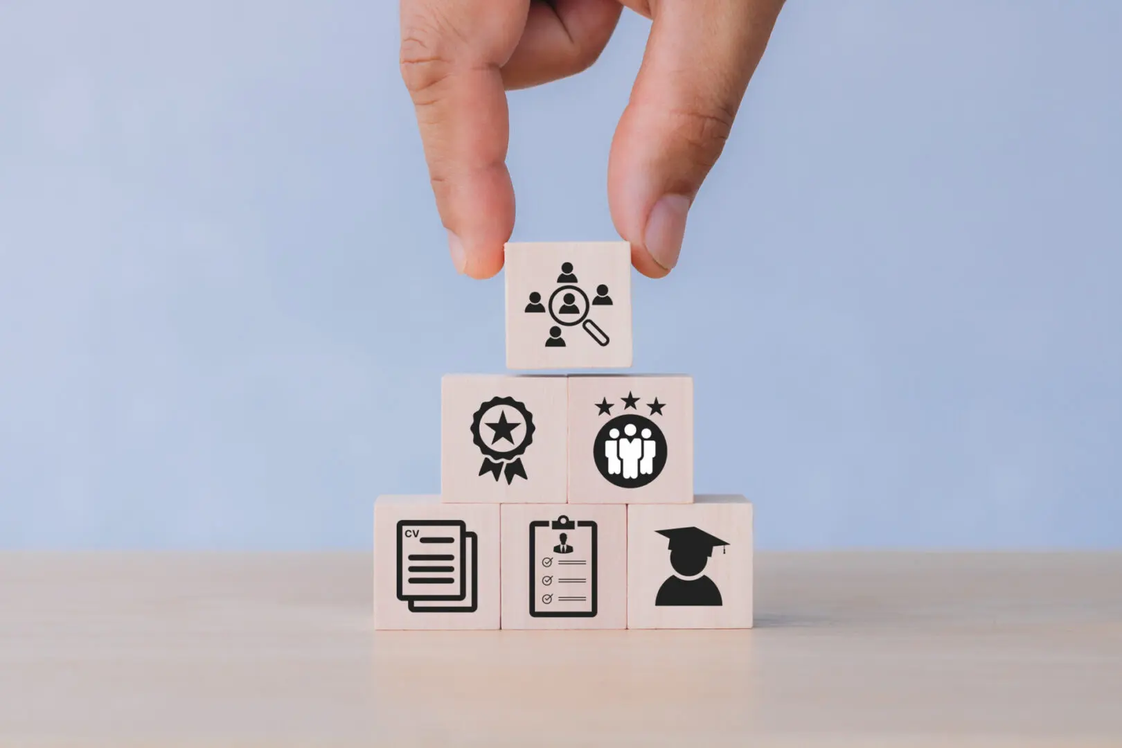 Hand stacking blocks with business icons.