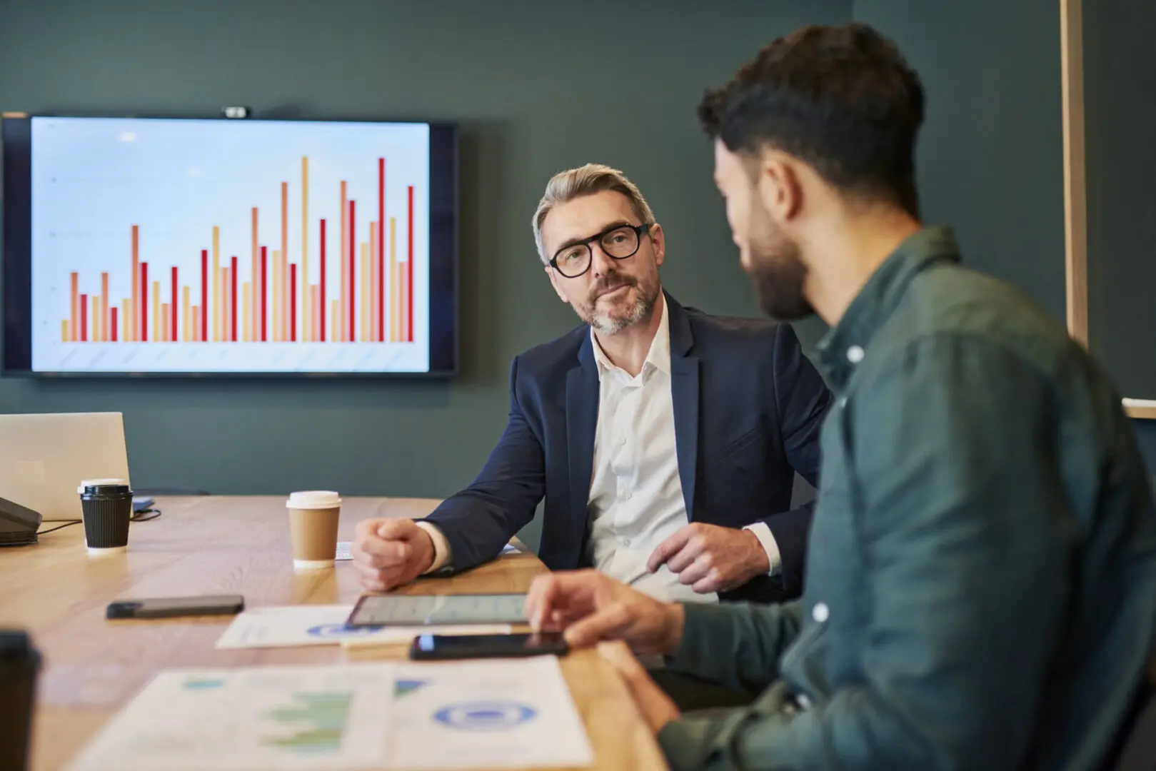 Two men discussing business with bar chart.