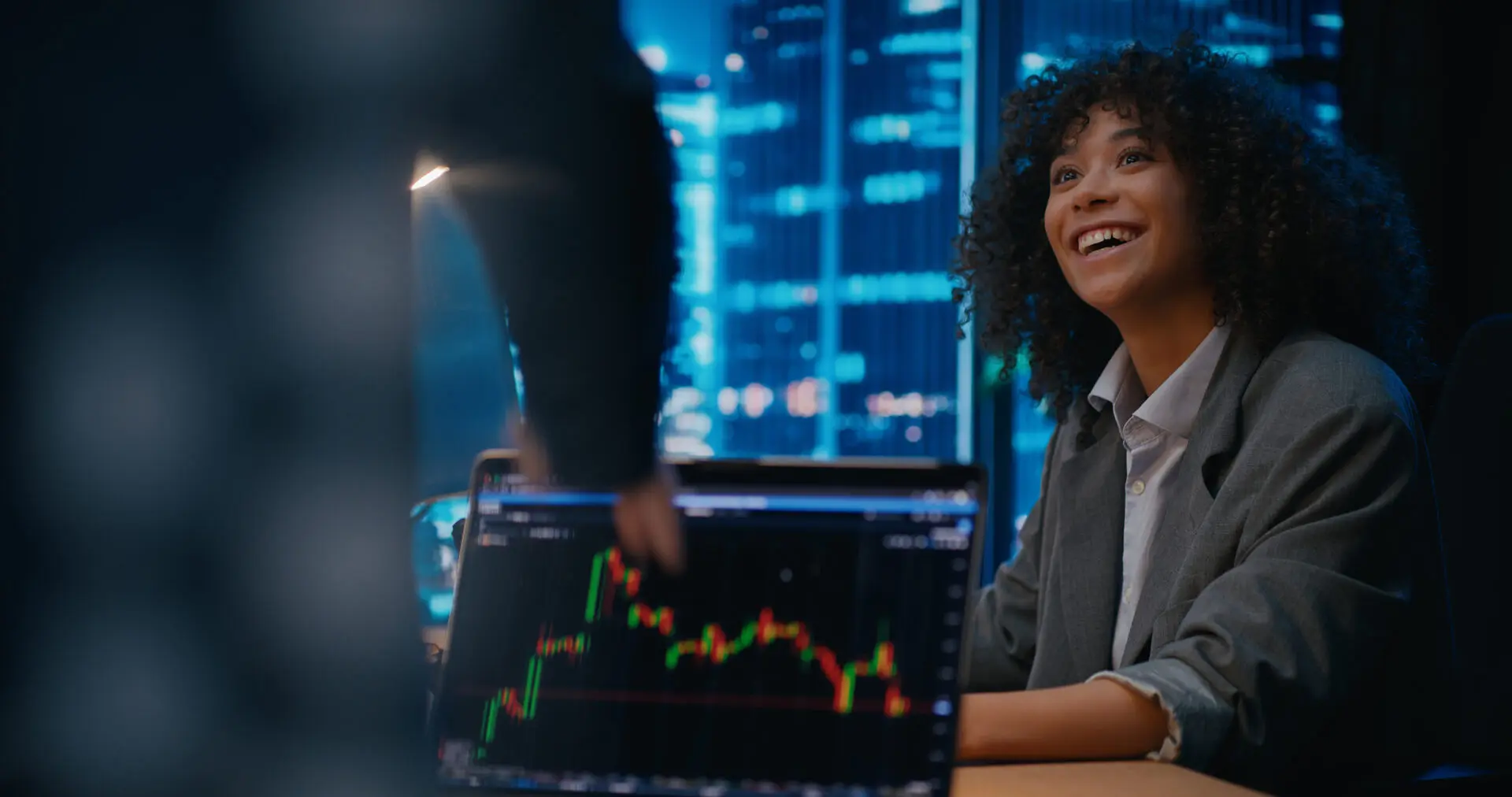 Smiling woman at desk with stock chart.