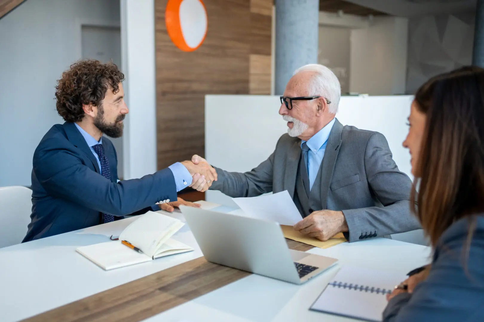 Businessmen shaking hands in modern office.